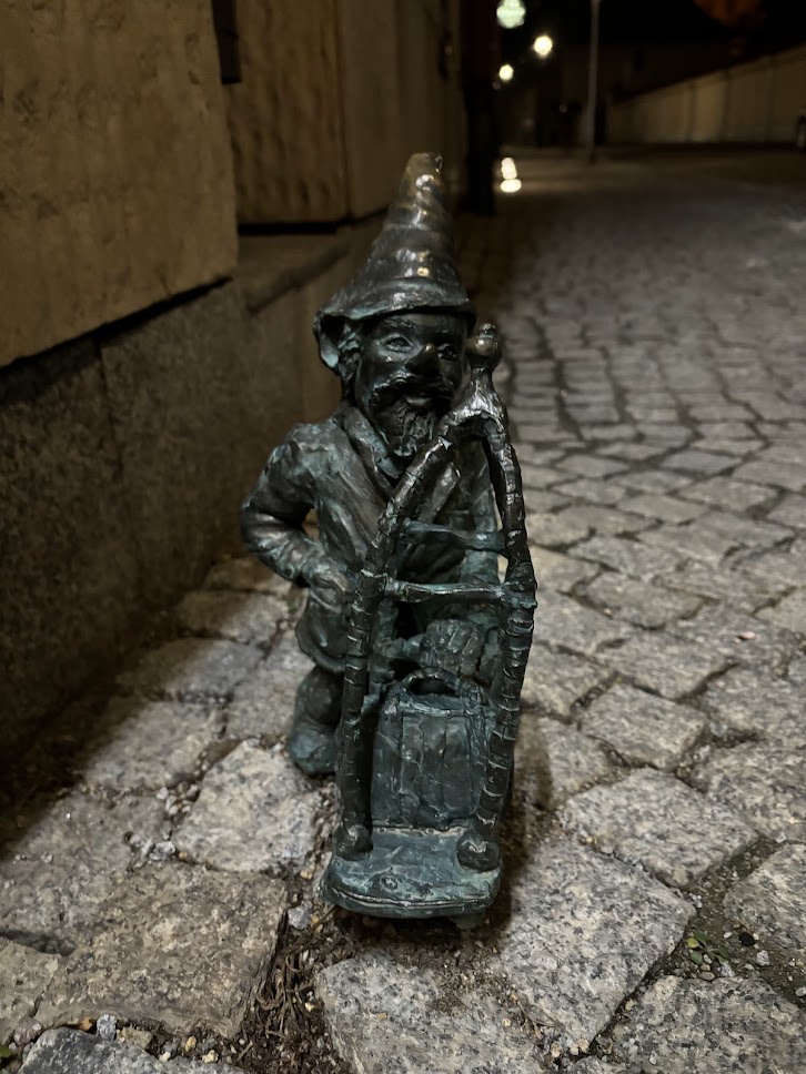 A bronze dwarf statue sitting and smiling in Wrocław