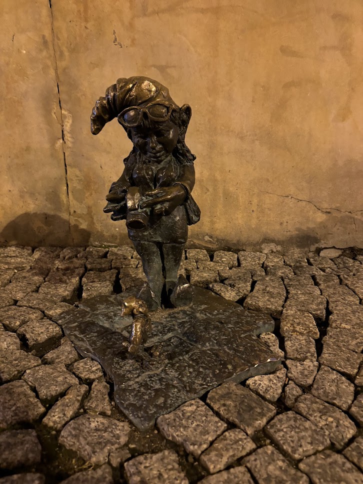 A dwarf statue staring at you with arms crossed