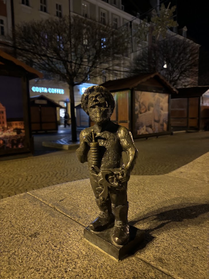 A dwarf statue with a camera taking photos