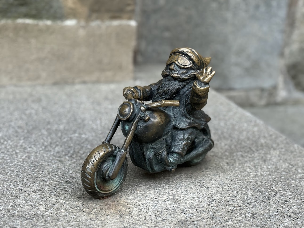 A bronze dwarf statue reading a book in Wrocław